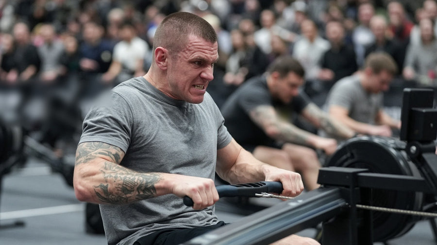 Hybrid race athlete pulling hard on a rowing machine on an indoor race floor